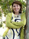 Woman with brown hair wearing green sweater and multi-color dress