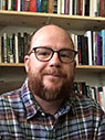 Man with black glasses and beard wearing plaid shirt