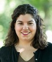 Woman with shoulder length brown curly hair wearing black cardigan